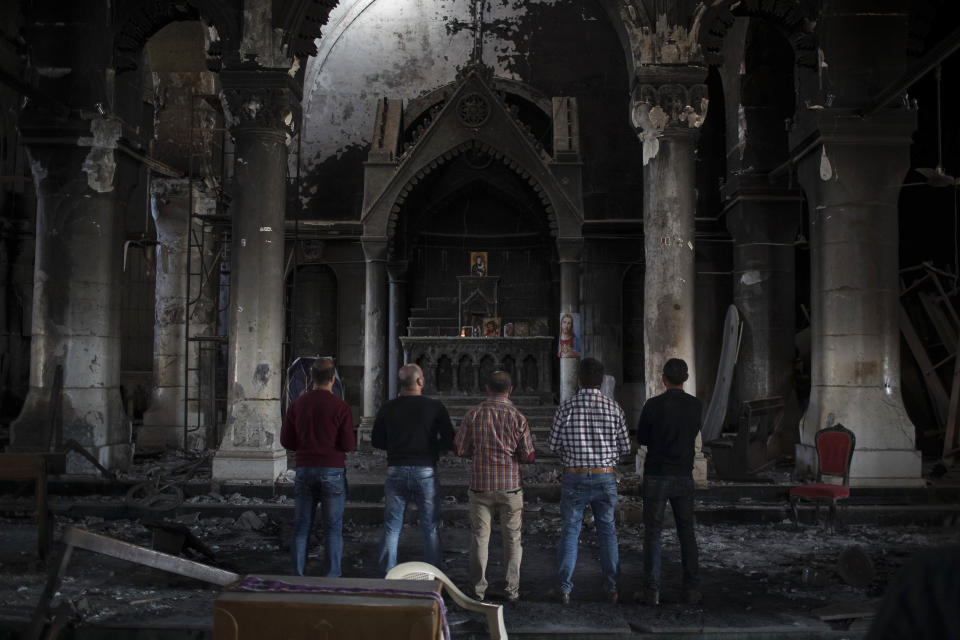 FILE - In this Nov. 12, 2016 file photo, Iraqi Christians pray at the Church of the Immaculate Conception, damaged by Islamic State fighters during their occupation of Qaraqosh, east of Mosul, Iraq. Pope Francis is pushing ahead with the first papal trip to Iraq despite rising coronavirus infections, hoping to encourage the country’s dwindling number of Christians who were violently persecuted during the Islamic State insurgency while seeking to boost ties with the Shiite Muslim world. (AP Photo/Felipe Dana)