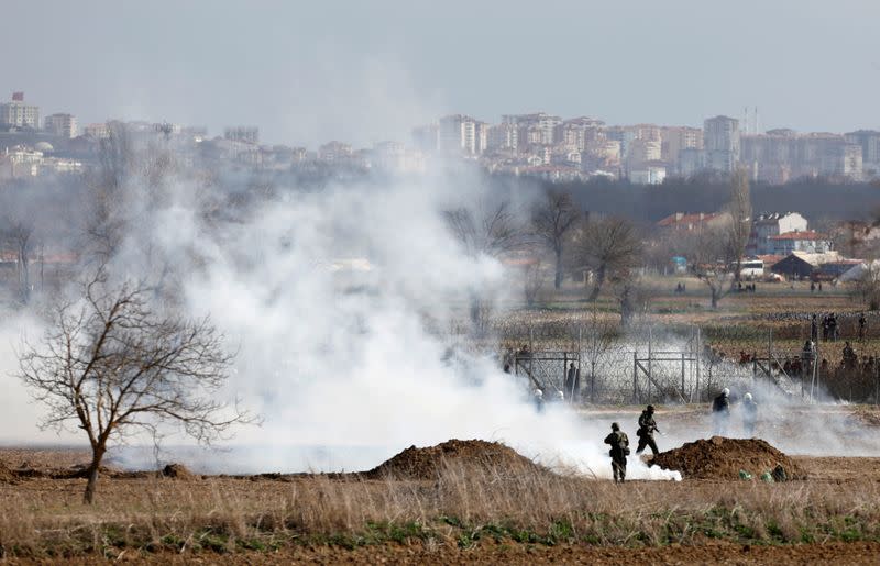 Greek soldiers and riot police officers stand amid clouds of tear gas near Turkey's Pazarkule border crossing, in Kastanies