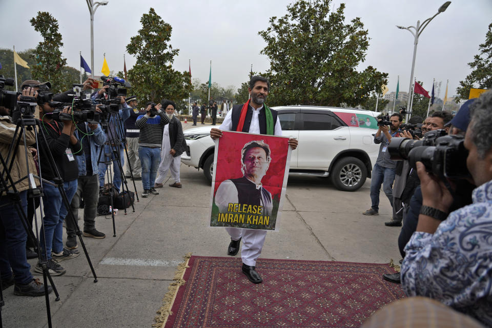 Pakistan's newly elected lawmaker Khurram Shahzad Wirk displays a poster of his leader and imprisoned former Prime Minister Imran Khan as he arrives to attend opening session of the Parliament, in Islamabad, Pakistan, Thursday, Feb. 29, 2024. Pakistan's National Assembly swore in newly elected members on Thursday in a chaotic scene, as allies of jailed former Premier Khan protested what they claim was a rigged election. (AP Photo/Anjum Naveed)