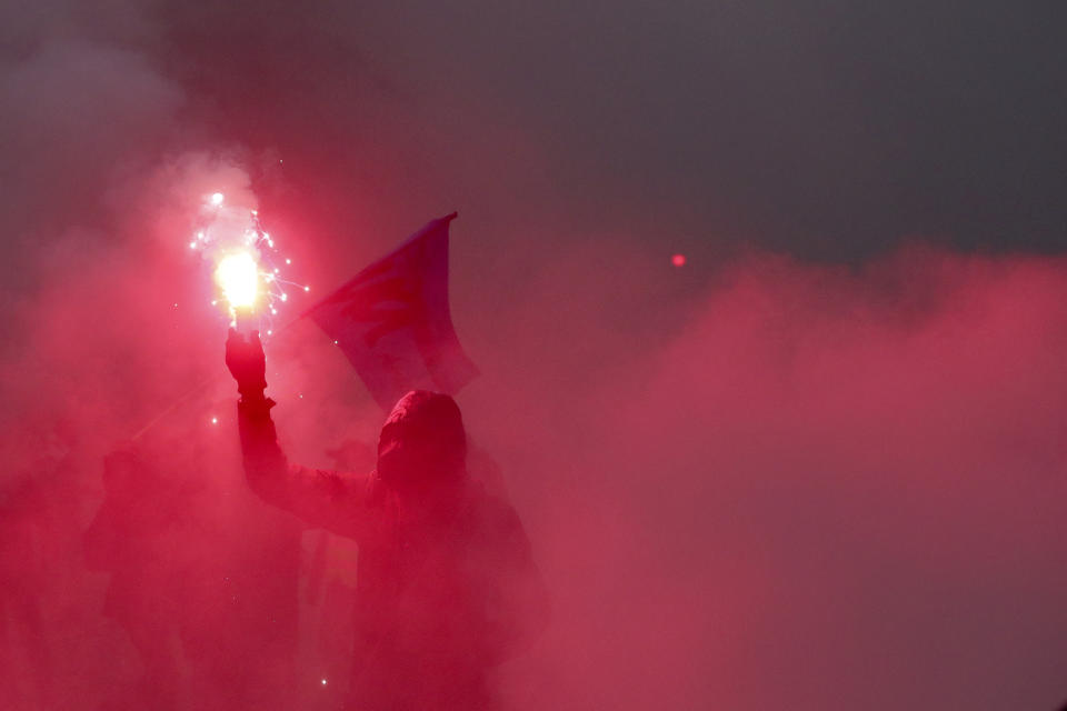 A demonstrator holds a flare during a demonstration in Paris, Thursday, Dec. 5, 2019. The Eiffel Tower shut down, France's high-speed trains stood still and tens of thousands of people marched through Paris and other cities Thursday, in a massive and sometimes chaotic outpouring of anger at the government's plan to overhaul the retirement system. (AP Photo/Thibault Camus)