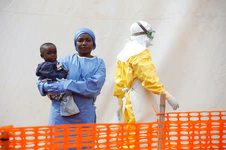Mwamini Kahindo, an Ebola survivor working as a caregiver to babies who are confirmed Ebola cases, holds an infant outside the red zone at the Ebola treatment centre in Butembo, Democratic Republic of Congo, March 25, 2019. Picture taken March 25, 2019. REUTERS/Baz Ratner