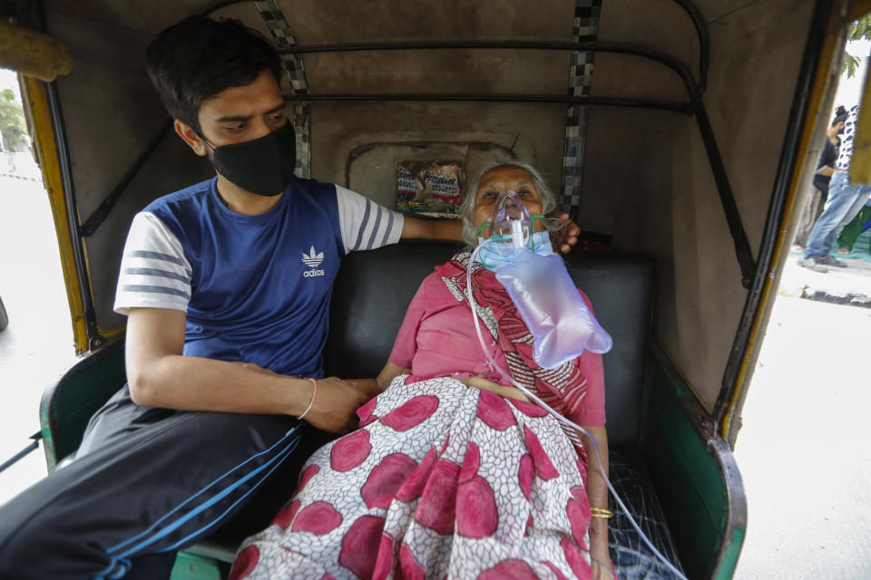 A COVID-19 patient waits inside an autorickshaw to be attended to and admitted into a dedicated COVID-19 government hospital in Ahmedabad, India, Saturday, April 17, 2021. India has been overwhelmed by hundreds of thousands of new coronavirus cases daily, bringing pain, fear and agony to many lives as lockdowns have been placed in Delhi and other cities around the country. (AP Photo/Ajit Solanki)