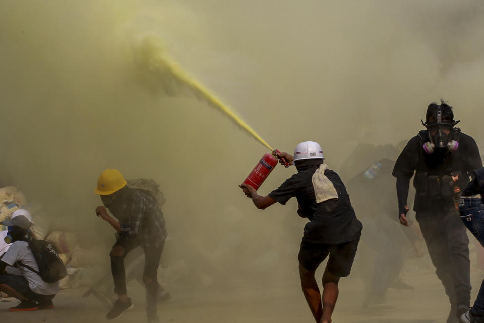 FILE - In this March 17, 2021, file photo, an anti-coup protester uses a fire extinguisher to provide cover for others as security forces approach their encampment in Yangon, Myanmar. Garment workers in Myanmar are urging major international brands to denounce the recent military coup there and put more pressure on factories to protect workers from being fired or harassed - or worse arrested and killed for participating in protests. Violent crackdowns by Myanmar security forces against protesters including garment workers are escalating. (AP Photo, File)