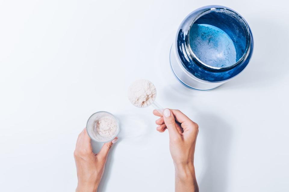 Female hand holding scoop with powder of sports supplements