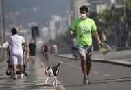 A man jogs with his dog in the bike lane that runs along the seashore at Ipanema beach in Rio de Janeiro, Brazil, Tuesday, June 2, 2020, amid the new coronavirus pandemic. Rio, the city with the second-most cases after Sao Paulo, is beginning to gradually relax restrictions on Tuesday, allowing people to exercise on the beachfront sidewalk and practice individual activities in the sea. (AP Photo/Silvia Izquierdo)