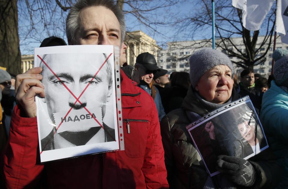 FILE - In this Feb. 29, 2020, file photo, protester holds a poster reading "Tired of" during a rally in memory of opposition leader Boris Nemtsov in St. Petersburg, Russia. Putin is just a step away from bringing about the constitutional changes that would allow him to extend his rule until 2036. The vote that would reset the clock on Putin’s tenure in office and allow him to serve two more six-year terms is set to wrap up Wednesday, July 1, 2020. (AP Photo/Dmitri Lovetsky, File)