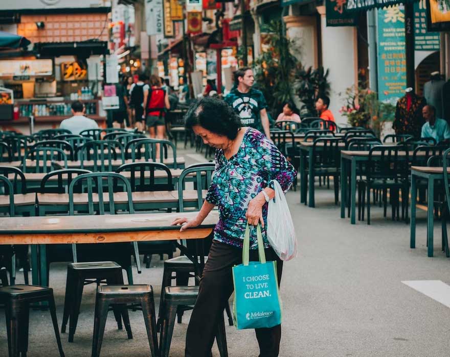 lady in chinatown looking down stretching dollar cost of living singapore