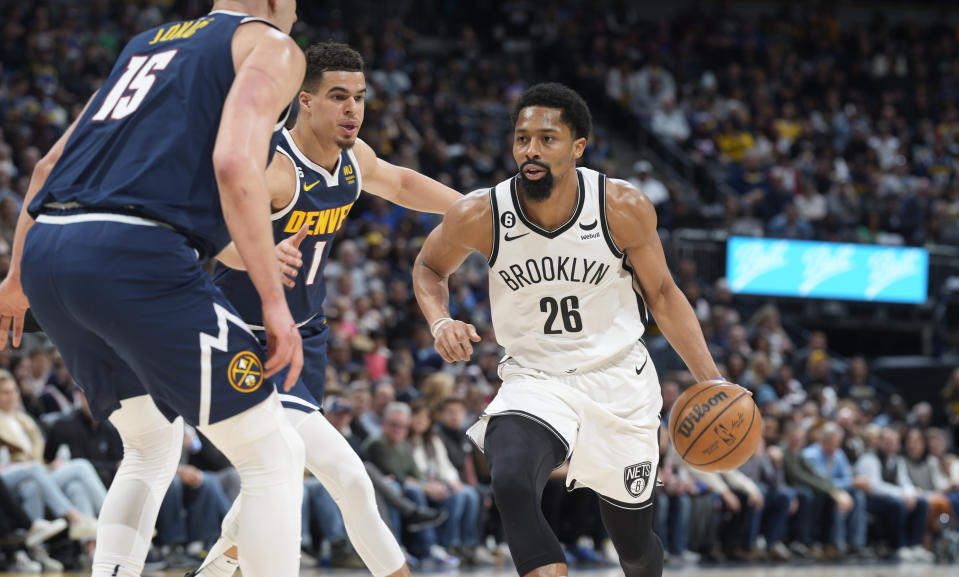 Brooklyn Nets guard Spencer Dinwiddie, right, drives to the rim as Denver Nuggets center Nikola Jokic, left, and forward Michael Porter Jr. defend in the first half of an NBA basketball game, Sunday, March 12, 2023, in Denver. (AP Photo/David Zalubowski)