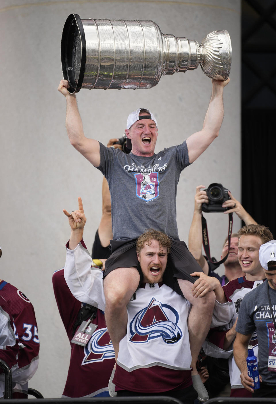 Colorado Avalanche skills coach Shawn Allard, top, lifts the Stanley Cup while sitting on the shoulder of right wing Mikko Rantanen during a rally outside the City/County Building for the NHL hockey champions after a parade through the streets of downtown Denver, Thursday, June 30, 2022. (AP Photo/David Zalubowski)