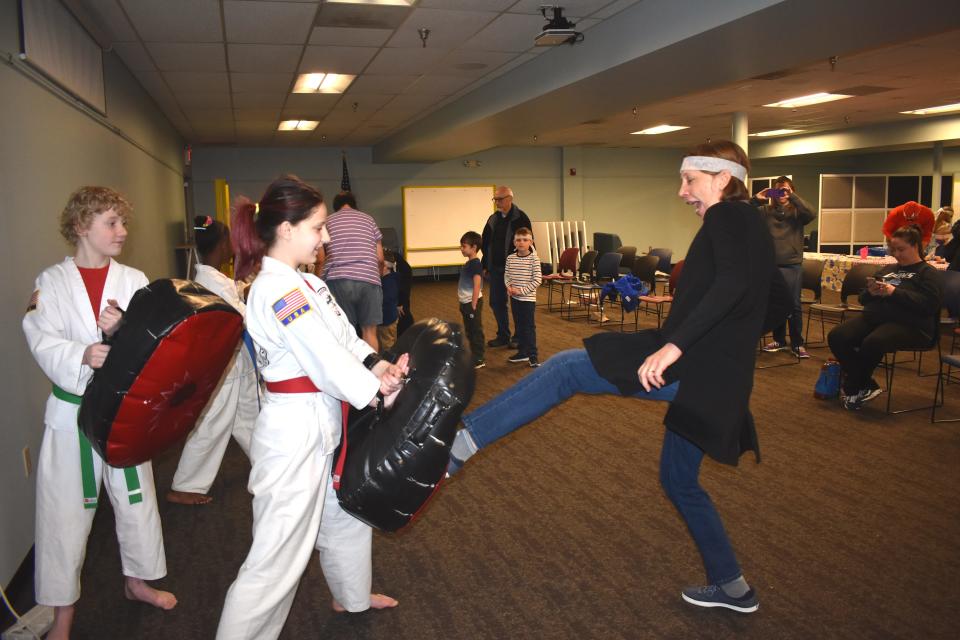 Adrian District Library Youth Services Librarian Cathy Chesher gets involved with the library's "Ninja Saturday at the Library" program April 30 by practicing a front kick technique with assistance from Michael Thorton and Miranda Stone, two students enrolled at Black Dragon's Den Martial Arts Academy in Adrian.