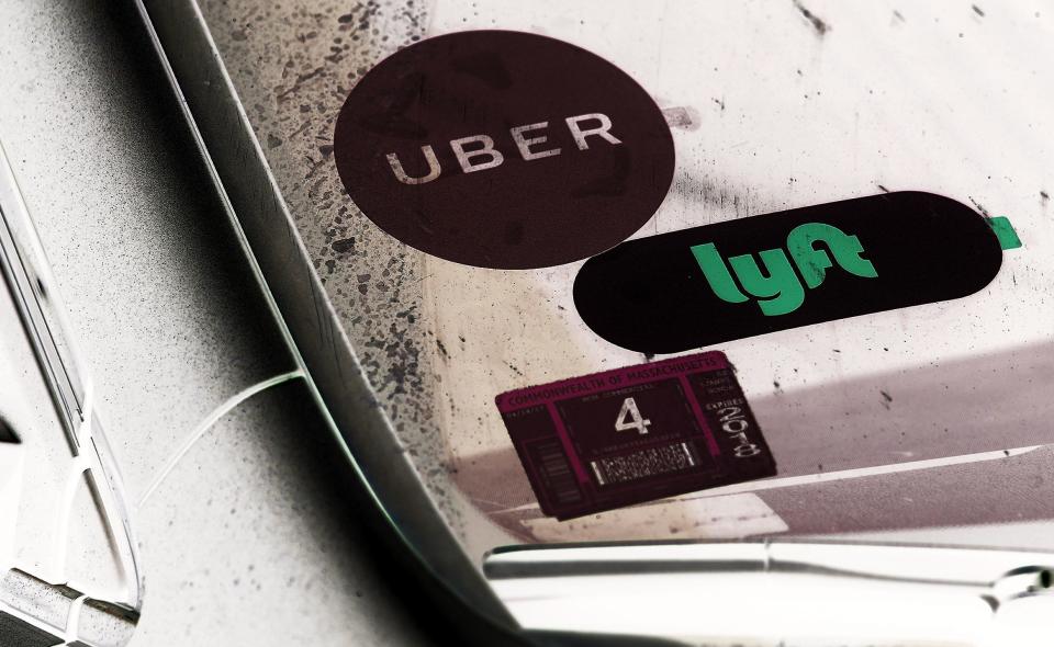 A driver with placards for both Lyft and Uber waits for a traffic light outside South Station in Boston after picking up a passenger on Jun. 15, 2017. (Photo by Lane Turner/The Boston Globe via Getty Images/photo inverted by Yahoo Finance) 