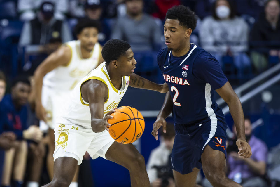 Notre Dame's Markus Burton (3) gets a pass around Virginia's Reece Beekman (2) during the first half of an NCAA college basketball game on Saturday, Dec. 30, 2023, in South Bend, Ind. (AP Photo/Michael Caterina)