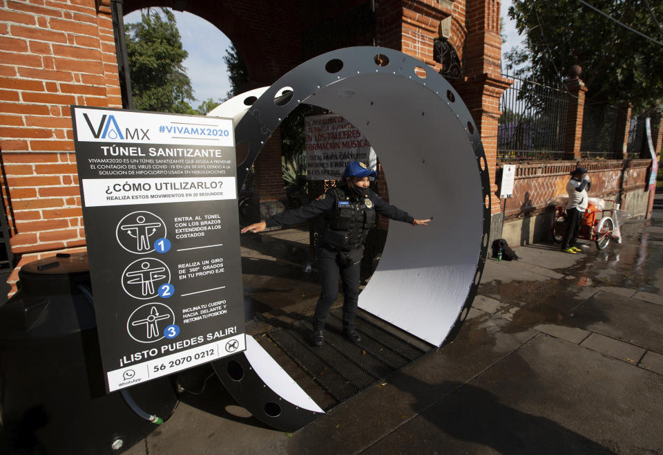 A police officer, wearing a protective face mask, steps into a sanitizing tunnel as a preventive measure against the spread of the new coronavirus, as she arrives for her shift, in Mexico City, Saturday, April 4, 2020. Mexico has started taking tougher measures against the new coronavirus, but some experts warn the country is acting too late and testing too little to prevent the type of crisis unfolding across the border in the United States. (AP Photo/Fernando Llano)