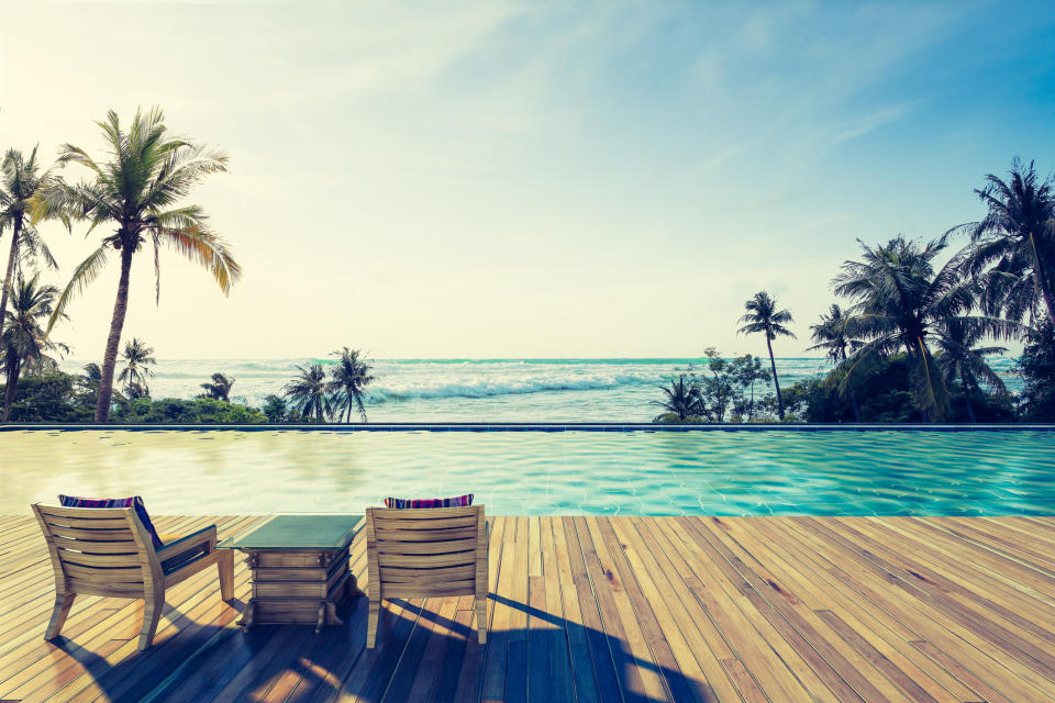 Swimming pool in tropics with ocean in the background.