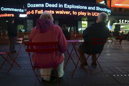 People watch as a news ticker updates people with the news of the shooting attacks in Paris, in Times Square in the Manhattan borough of New York November 13, 2015. REUTERS/Carlo Allegri