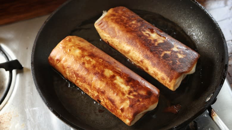 two chimichangas in skillet