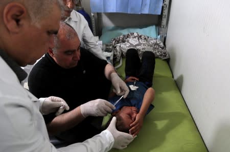 Doctors treat a wounded Syrian refugee girl at a mobile clinic in north Azaz