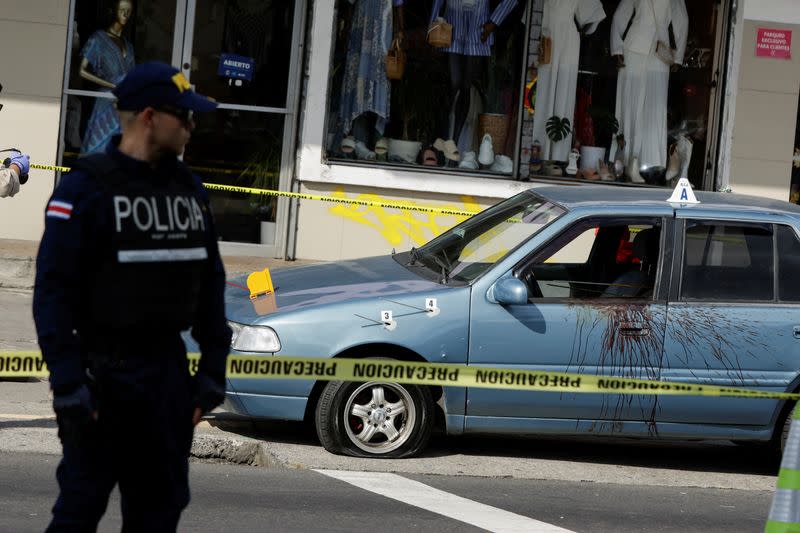 A police officer guards a scene where unknown assailants opened fire and injured two persons traveling in a car, in San Jose