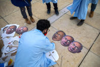 Israeli demonstrators prepare masks depicting Israeli Prime Minister Benjamin Netanyahu and Israeli Defense Minister Benny Gantz during a protest against a parliamentary vote to dissolve the Knesset and send the country to its fourth elections in two years while it still hasn't approved a national budget for 2020, in Tel Aviv, Wednesday, Dec. 2, 2020. (AP Photo/Oded Balilty)