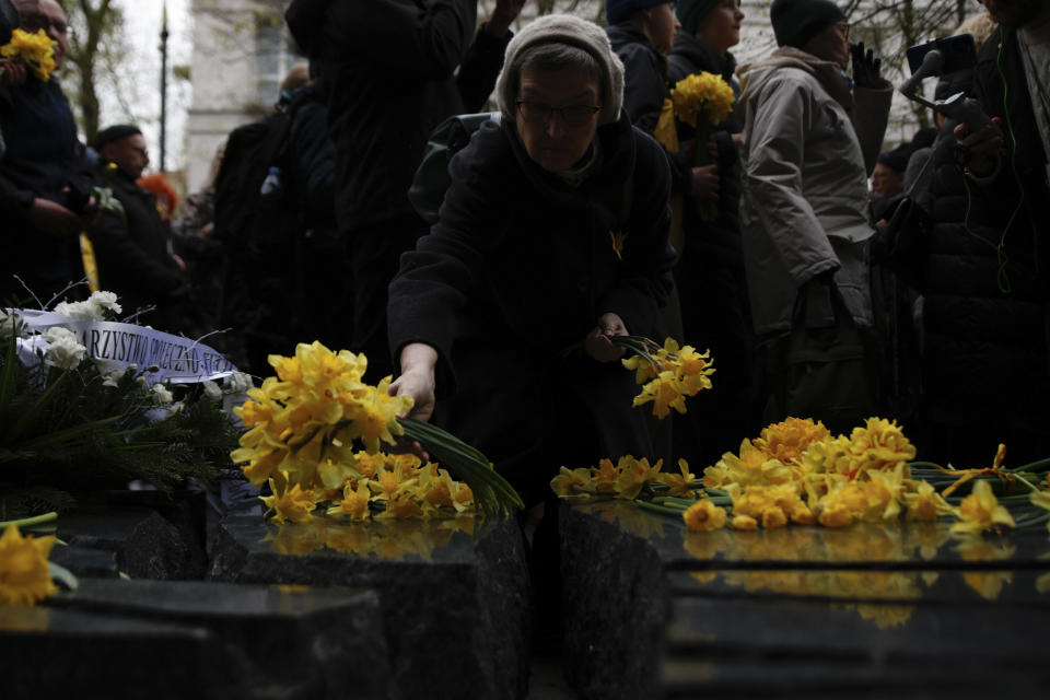 A woman places yellow tulips at The Monument to Szmul Zygielbojm during personal unofficial observances marking the 80th anniversary of the Warsaw Ghetto Uprising in Warsaw, Poland, Wednesday, April 19, 2023. (AP Photo/Michal Dyjuk)