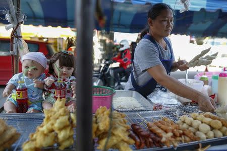 Hong, 42, a street food stall owner, works next to her "child angel" dolls near Wat Bua Khwan temple in Nonthaburi, Thailand, January 26, 2016. REUTERS/Athit Perawongmetha
