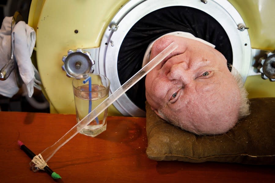FILE – In this Friday, April 27, 2018 photo, attorney Paul Alexander looks out from inside his iron lung at his home in Dallas. Alexander died Monday, March 11, 2024 at a Dallas hospital, said Daniel Spinks, a longtime friend. He said Alexander had recently been hospitalized after being diagnosed with COVID-19 but did not know the cause of death. (Smiley N. Pool/The Dallas Morning News via AP)