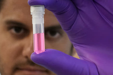 Andrew Schweighardt holds a vial with a DNA sample at the office of the Chief Medical Examiner of New York during an event in New York City, New York, U.S., September 6, 2018. REUTERS/Carlo Allegri