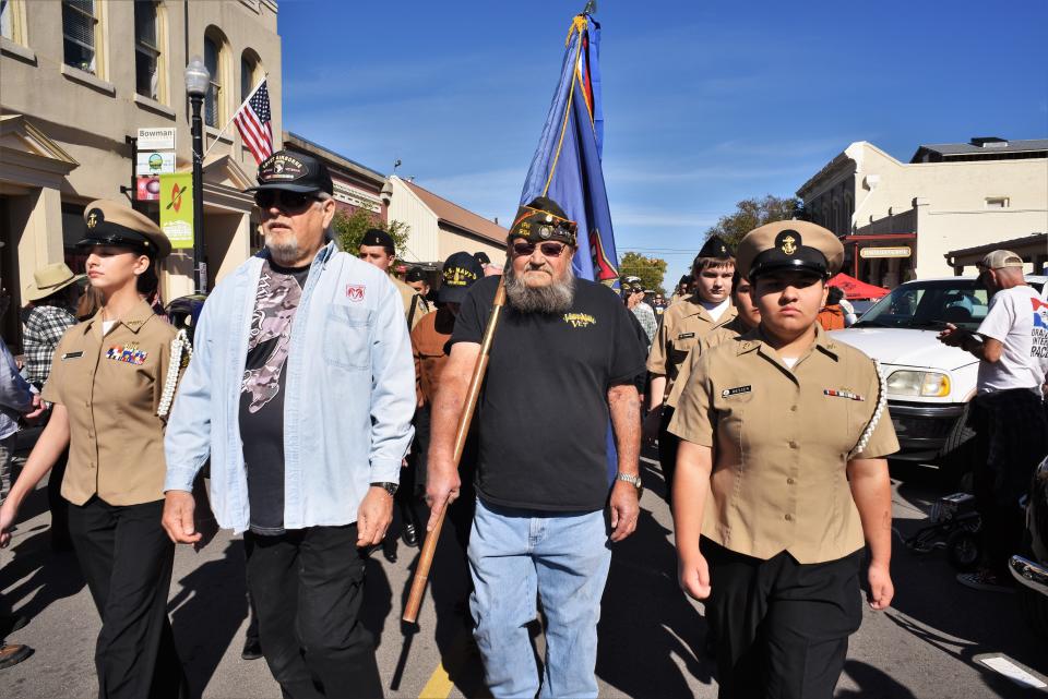 Military veterans march with Bastrop High School Naval ROTC cadets during the 15th annual Veterans Weekend Car Show. The procession made its way to the Bastrop County Courthouse grounds for a veterans recognition and awards ceremony.