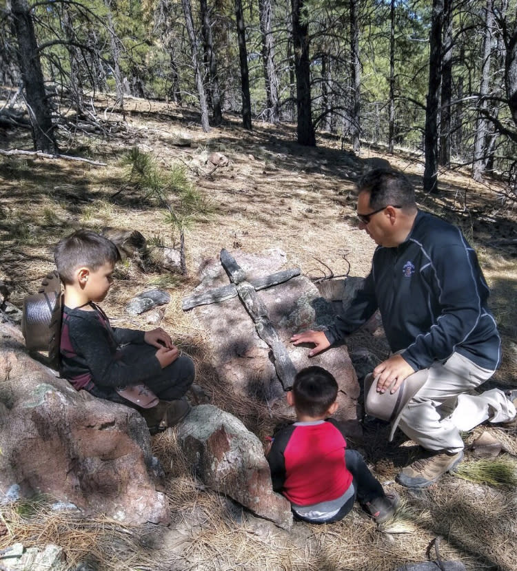 This undated photo provided by Fidel Trujillo shows Trujillo, far right, stopping to say a prayer in the forest near Ledoux, New Mexico, with his sons, Joseph, far left, and Jace. Residents of the community were forced to evacuate because of a wildfire that has marched across 258 square miles of high alpine forest and grasslands at the southern tip of the Rocky Mountains. (Fidel Trujillo via AP)