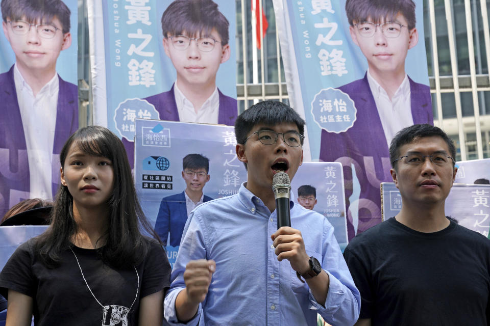 Hong Kong democratic activists, Joshua Wong, center, is accompanied with Agnes Chow, left and pro-democracy lawmaker Au Nok-hin, speaks to the media in Hong Kong, Saturday, Sept. 28, 2019. Wong announced plans to contest local elections and warns that any attempt to disqualify him will only spur more support for monthslong pro-democracy protests. (AP Photo/Kin Cheung)