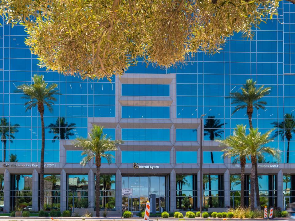 A modern, glass building with palm trees in front of it