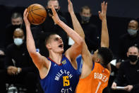 Denver Nuggets center Nikola Jokic shoots over Phoenix Suns guard Devin Booker (1) during the first half of an NBA basketball game Friday, Jan. 22, 2021, in Phoenix. (AP Photo/Rick Scuteri)