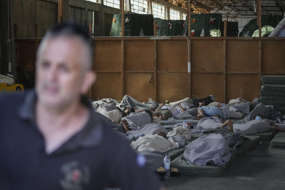 Survivors of a shipwreck sleep at a warehouse at the port in Kalamata town, about 240 kilometers (150 miles) southwest of Athens, Wednesday, June 14, 2023. A fishing boat carrying migrants capsized and sank off the coast of Greece on Wednesday, authorities said, leaving at least 78 people dead and many dozens feared missing in one of the worst disasters of its kind this year. (AP Photos/Thanassis Stavrakis)