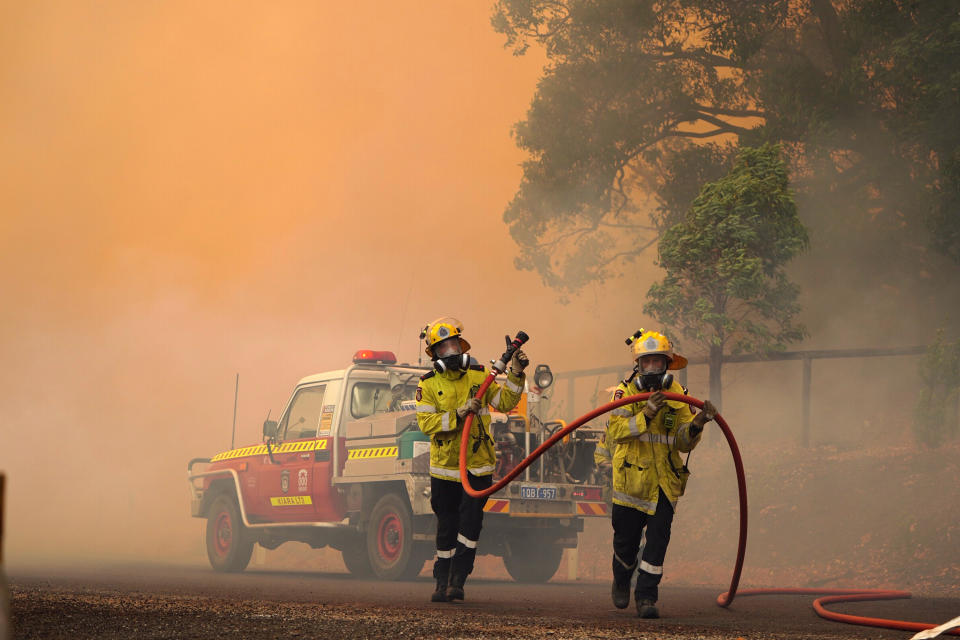 In this photo provided by Department of Fire and Emergency Services, firefighters attend to a fire near Wooroloo, northeast of Perth, Australia, Tuesday, Feb. 2, 2021. An out-of-control wildfire burning northeast of the Australian west coast city of Perth has destroyed dozens of homes and was threatening more. (Evan Collis/DFES via AP)