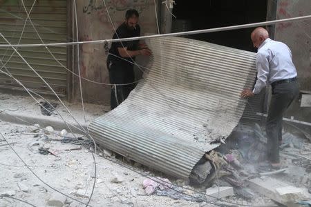 Residents inspect a shop at a site hit by airstrikes, in the rebel-held area of Aleppo's Bustan al-Qasr, Syria April 29, 2016. REUTERS/Abdalrhman Ismail