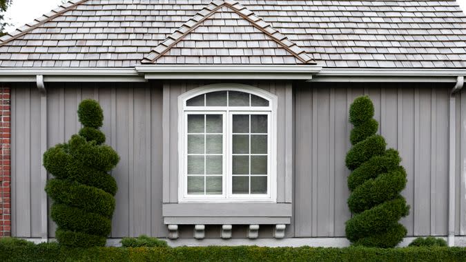 Centered view on the exterior of a craftsmen style home framed by spiral bushes, in a residential architectural background - Image.