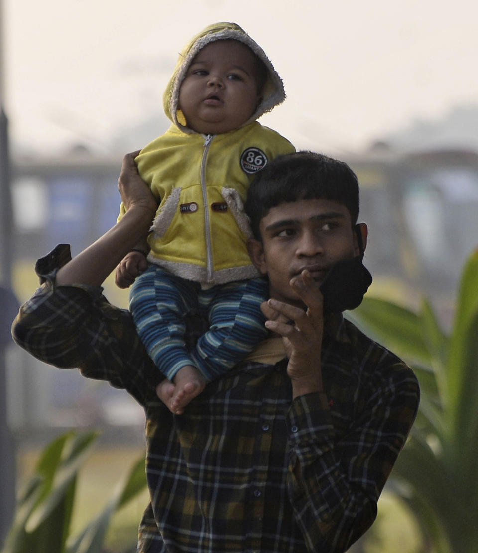 A Rohingya refugee carries a child and walks to board a naval vessel to be relocated to to the island of Bhasan Char, in Chattogram, Bangladesh, Saturday, Jan. 30, 2021. Authorities in Bangladesh sent a group of Rohingya refugees to a newly developed island in the Bay of Bengal on Saturday despite calls by human rights groups for a halt to the process. The government insists the relocation plan is meant to offer better living conditions while attempts to repatriate more than 1 million refugees to Myanmar would continue. (AP Photo/Azim Aunon)