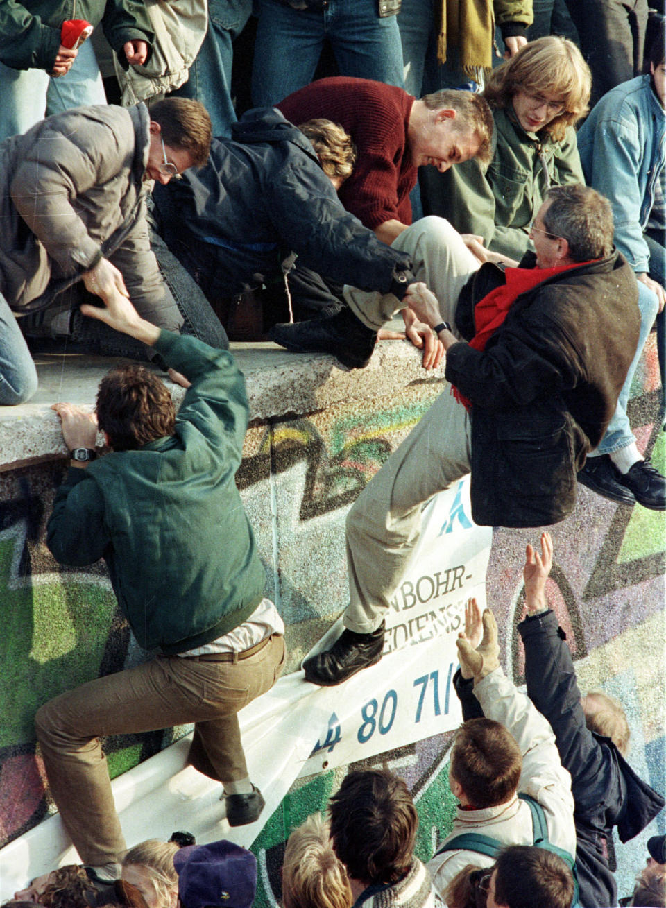 East German citizens help each other climb the Berlin Wall at the Brandenburg gate after the opening of East German borders in this early Nov. 10, 1989. (Photo: Reuters)