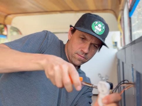 Scott working on the electrical wiring on the bus.