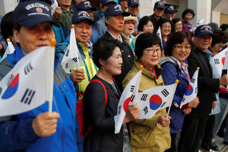 Supporters hold South Korean flags while waiting for a convoy transporting South Korean President Moon Jae-in to leave the Presidential Blue House for the inter-Korean summit, in Seoul, South Korea, April 27, 2018.