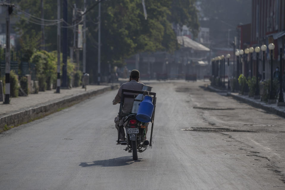 A Kashmiri milkman drives his motorcycle on a deserted street on the first anniversary of India’s decision to revoke the disputed region’s semi-autonomy, in Srinagar, Indian controlled Kashmir, Wednesday, Aug. 5, 2020. Last year on Aug. 5, India’s Hindu-nationalist-led government of Prime Minister Narendra Modi stripped Jammu-Kashmir of its statehood and divided it into two federally governed territories. Late Tuesday, authorities lifted a curfew in Srinagar but said restrictions on public movement, transport and commercial activities would continue because of the coronavirus pandemic. (AP Photo/ Dar Yasin)