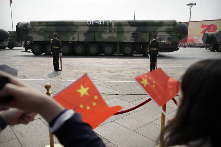 ARCHIVO - Espectadores ondean banderas chinas mientras vehículos militares con misiles balísticos DF-41 pasan durante un desfile por el 70mo aniversario de la fundación del Partuido Comunista de China en Pekín el 1 de octubre del 2019. (AP Foto/Mark Schiefelbein)