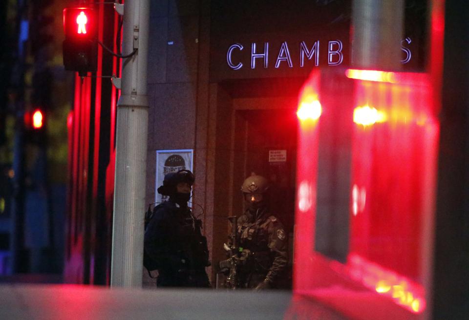 Heavily armed policemen stand guard outside the building containing the Lindt cafe, where hostages are being held, at Martin Place in central Sydney December 16, 2014. Australian police locked down the centre of the country's biggest city on Monday after an armed man walked into the downtown Sydney cafe, took hostages and forced them to display an Islamic flag, igniting fears of a jihadist attack. Police said they knew of one armed assailant involved in the incident at the Lindt chocolate cafe in the heart of Sydney's financial district, but there could be more. REUTERS/David Gray (AUSTRALIA - Tags: CIVIL UNREST POLITICS)