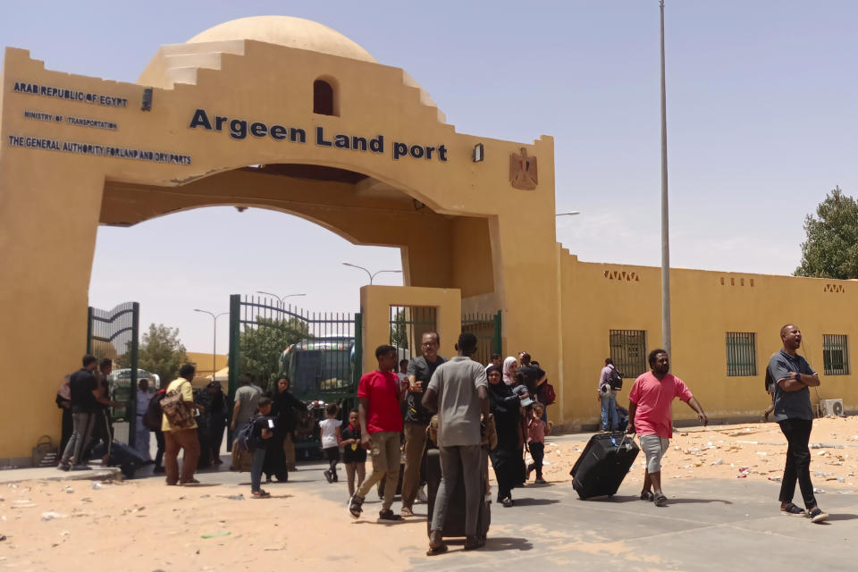 Evacuees carry their luggages as they cross into Egypt through the Argeen land port, after being evacuated from Sudan to escape the conflict, east of the High Dam Lake on the international border lines between Egypt and Sudan, Thursday, April 27, 2023. (AP Photo)