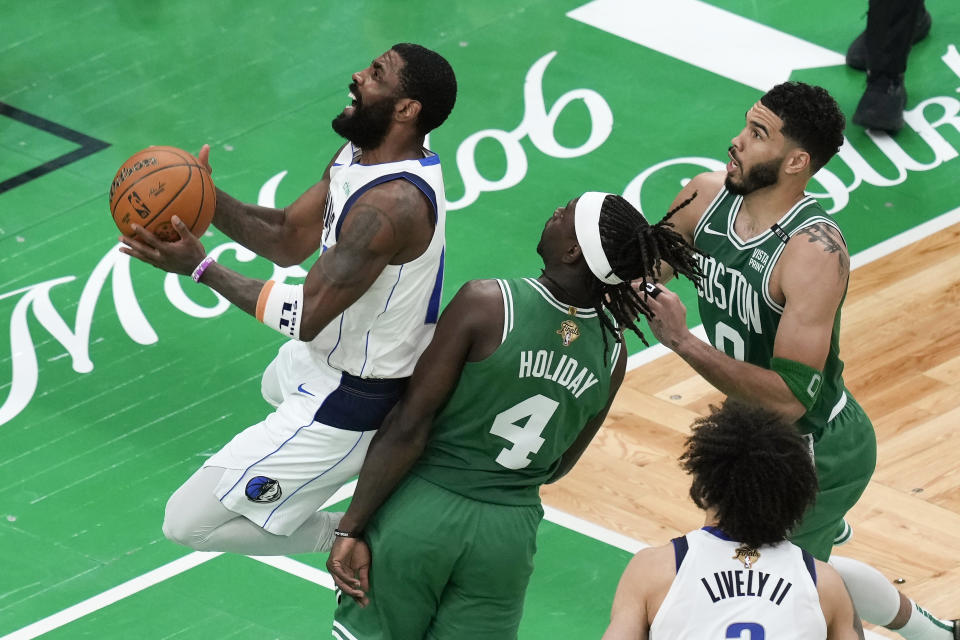 Dallas Mavericks' Kyrie Irving, left, shoots against Boston Celtics' Jrue Holiday (4) and Jayson Tatum (0) during the second half of Game 5 of the NBA basketball finals, Monday, June 17, 2024, in Boston. (AP Photo/Michael Dwyer)