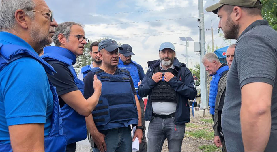 In this photo released by the International Atomic Energy Agency, the Director General of nuclear watchdog, Rafael Mariano Grossi, second from left, speaks to unidentified authorities as the UN agency mission heads to the Zaporizhzhia nuclear power plant, Zaporizhzhia, Ukraine, Thursday, Sept. 1, 2022. The IAEA mission has been delayed on the Ukrainian-controlled side of the frontline for some three hours. Director General Grossi has personally negotiated with Ukrainian military authorities to be able to proceed and he remains determined that this important mission reaches the ZNPP today, IAEA spokesman said.(International Atomic Energy Agency via AP)