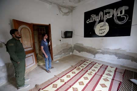 YPG is written over a wall painting of ISIS flag inside a house