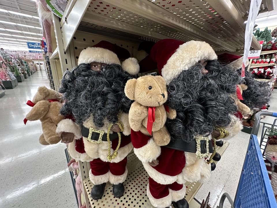 Santa figurines wit hgray beards holding teddy bears on a shelf