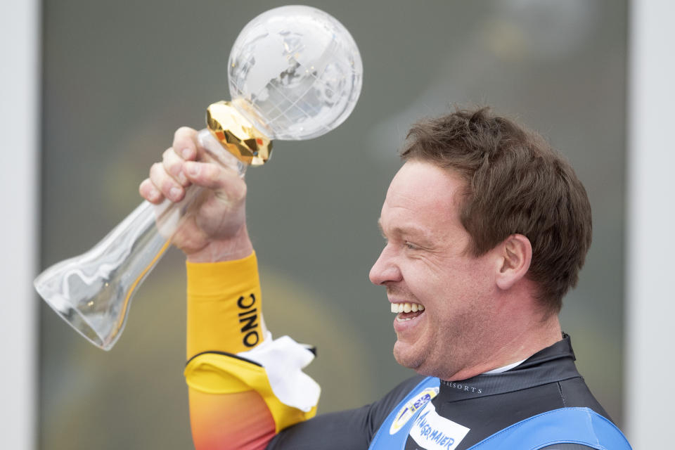 Felix Loch of Germany celebrates with the trophy for winning the world cup after the Luge World Cup event in Innsbruck, Austria, Saturday, Jan. 23, 2021. (AP Photo/Andreas Schaad)