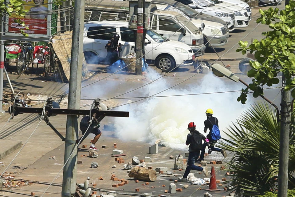 Anti-coup protesters run toward smoke from tear gas on a road full of debris in San Chaung township in Yangon, Myanmar Friday, March 5, 2021. Demonstrators defy growing violence by security forces and stage more anti-coup protests ahead of a special U.N. Security Council meeting on the country’s political crisis. (AP Photo)